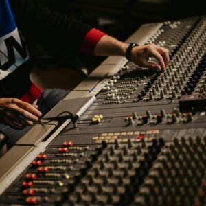 Sound engineer adjusting audio levels on a mixing console in a modern recording studio.